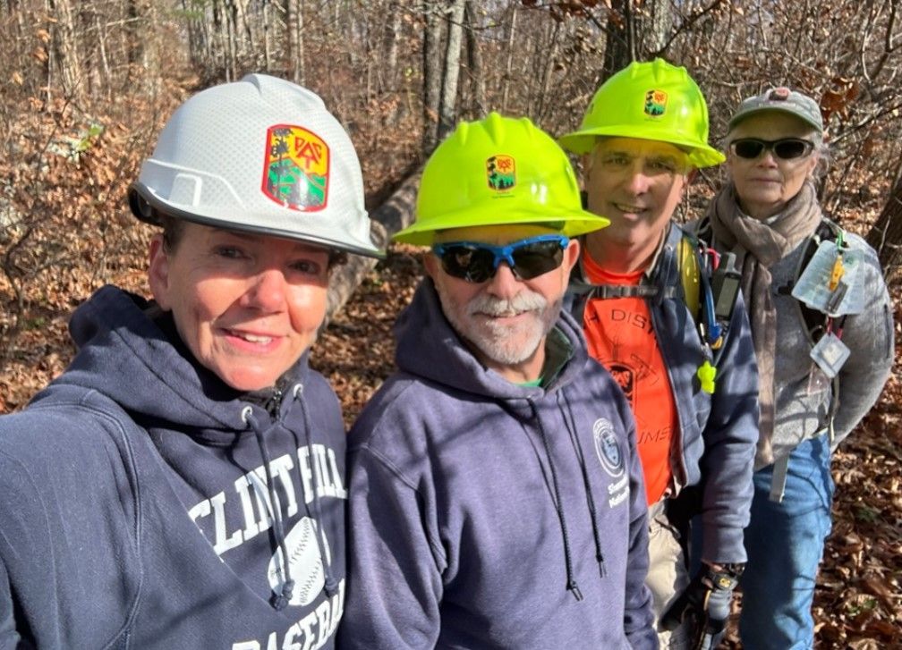 A group of people wearing hard hats and sunglasses are posing for a picture.
