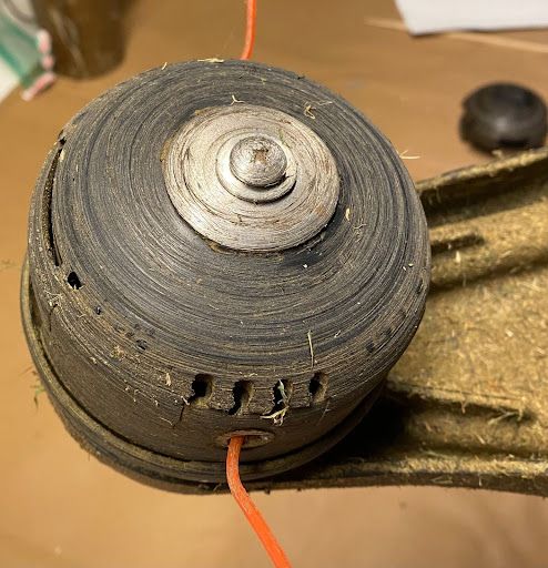 A close up of a lawn mower head with a wire coming out of it