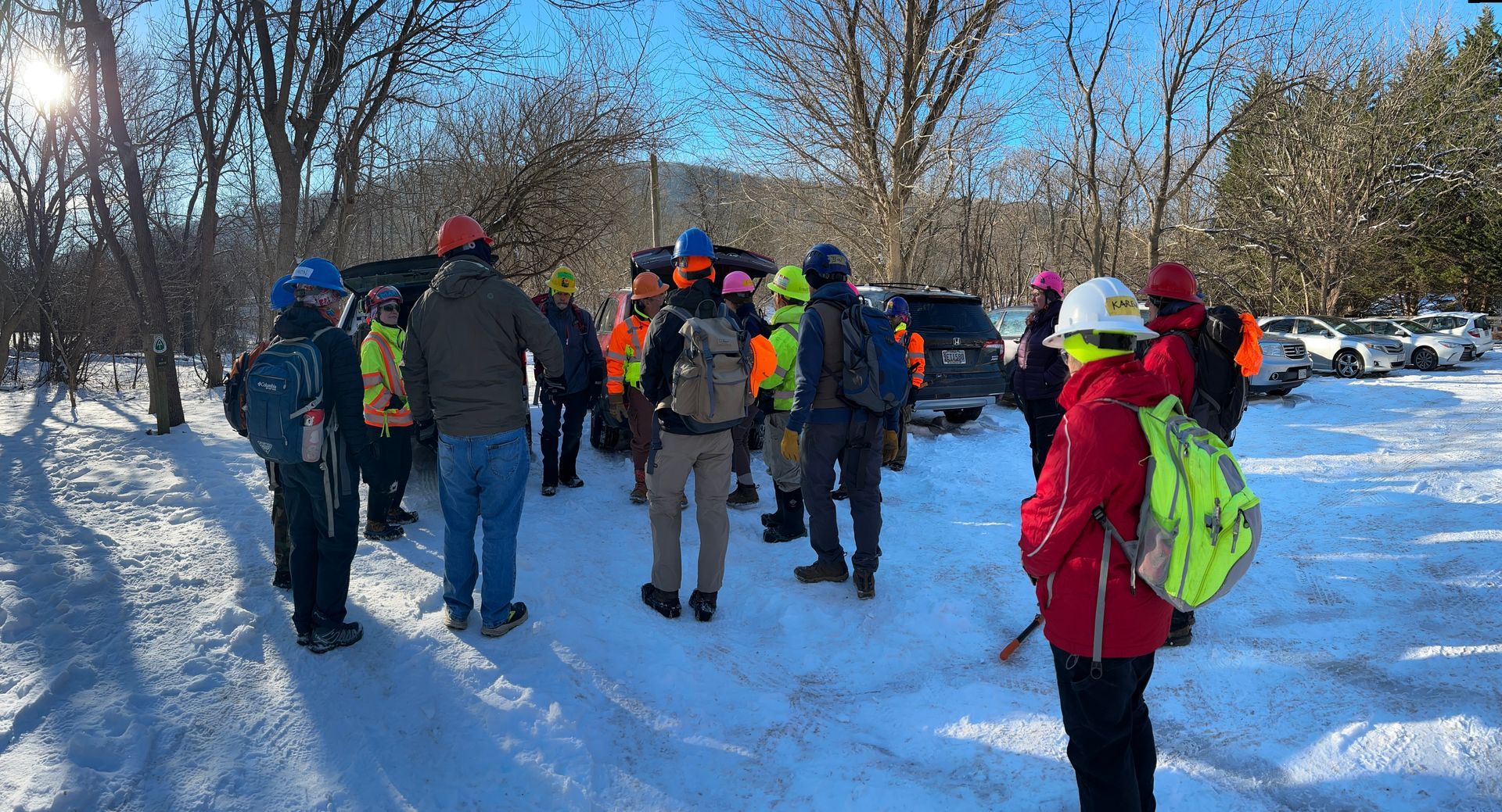 A group of people are standing in the snow in a parking lot.