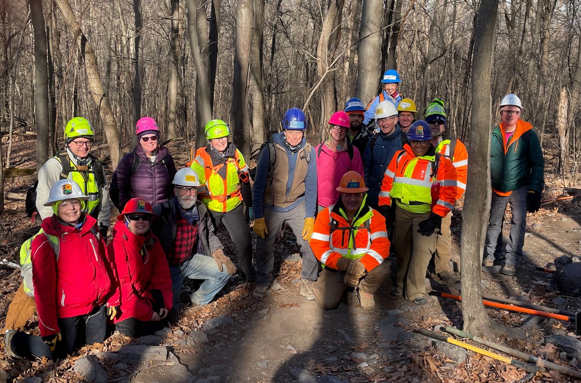 A group of people wearing hard hats are posing for a picture in the woods.