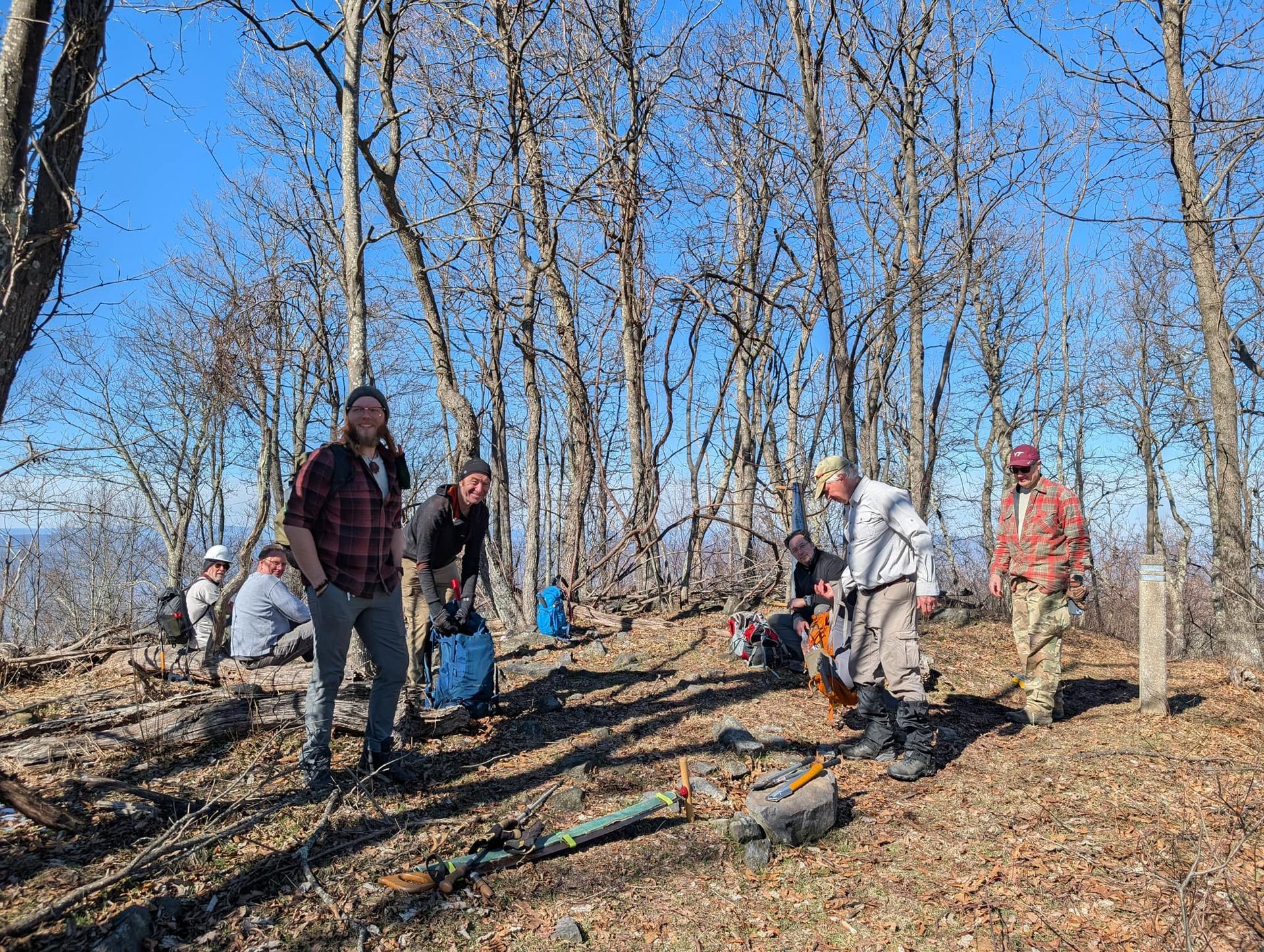 A group of people are standing on top of a hill in the woods.