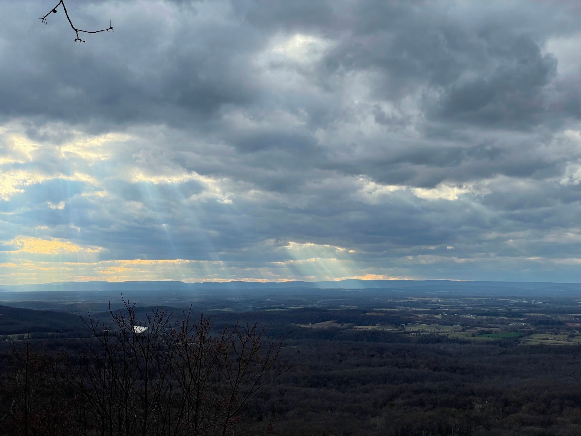 The sun is shining through the clouds over a valley
