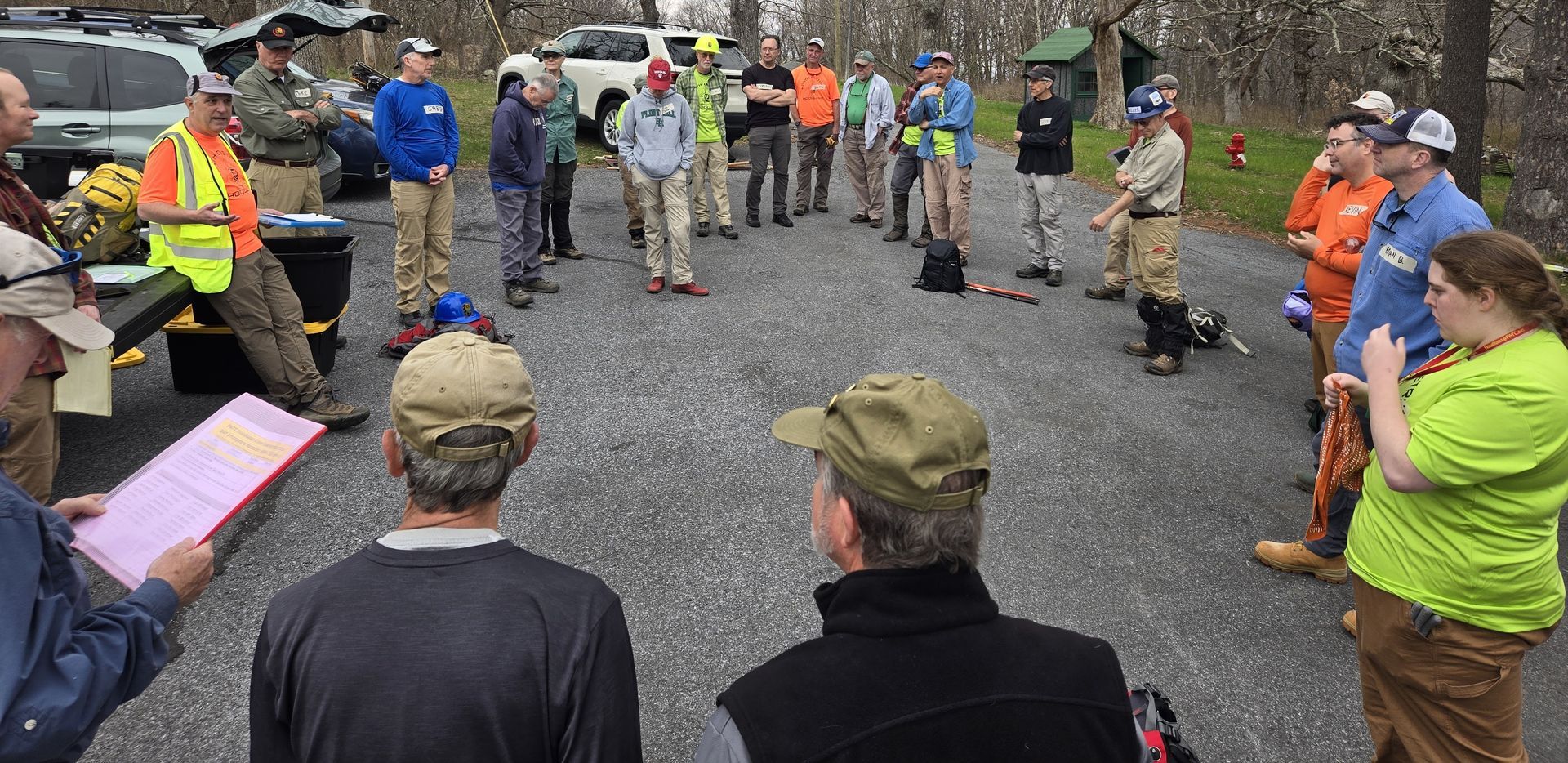 A group of people are standing in a circle on a gravel road.