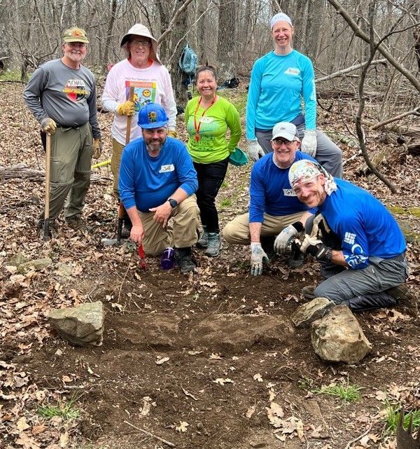 A group of people are posing for a picture in the woods.