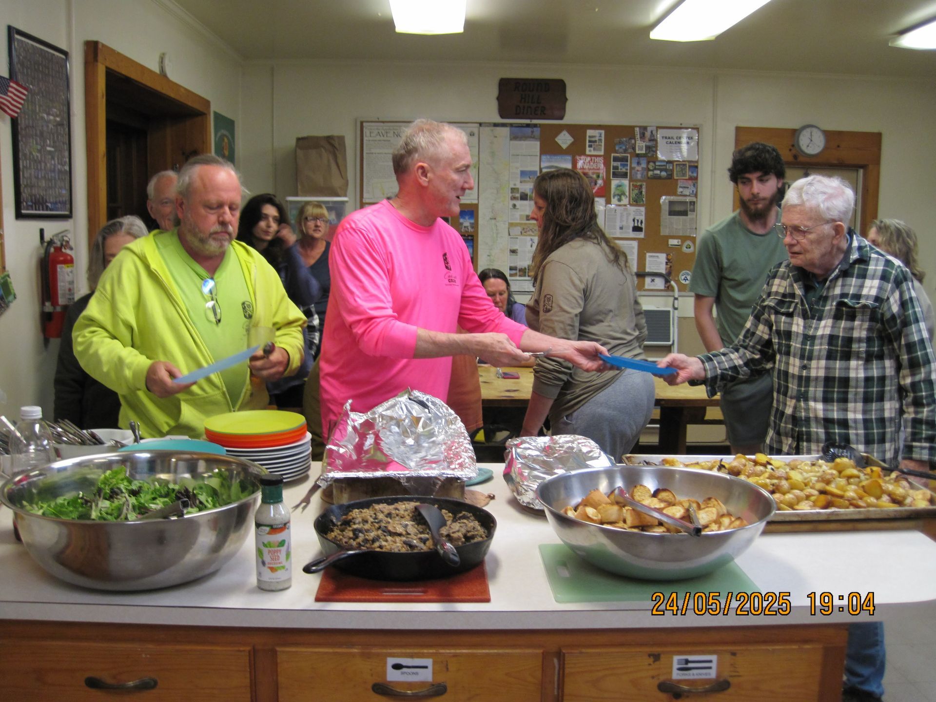 A man in a pink shirt is serving food to a group of people