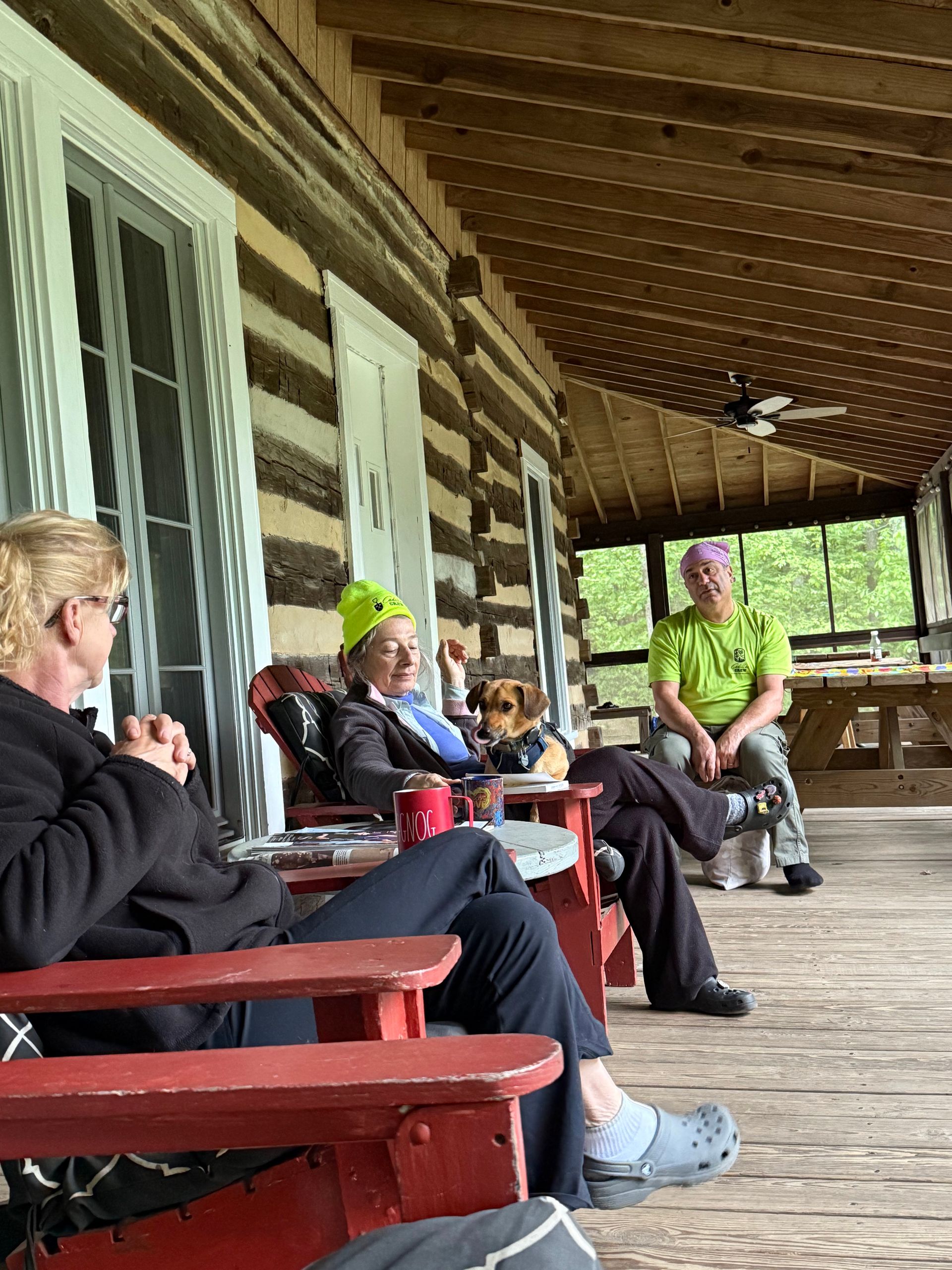 A group of people are sitting on a porch of a log cabin.
