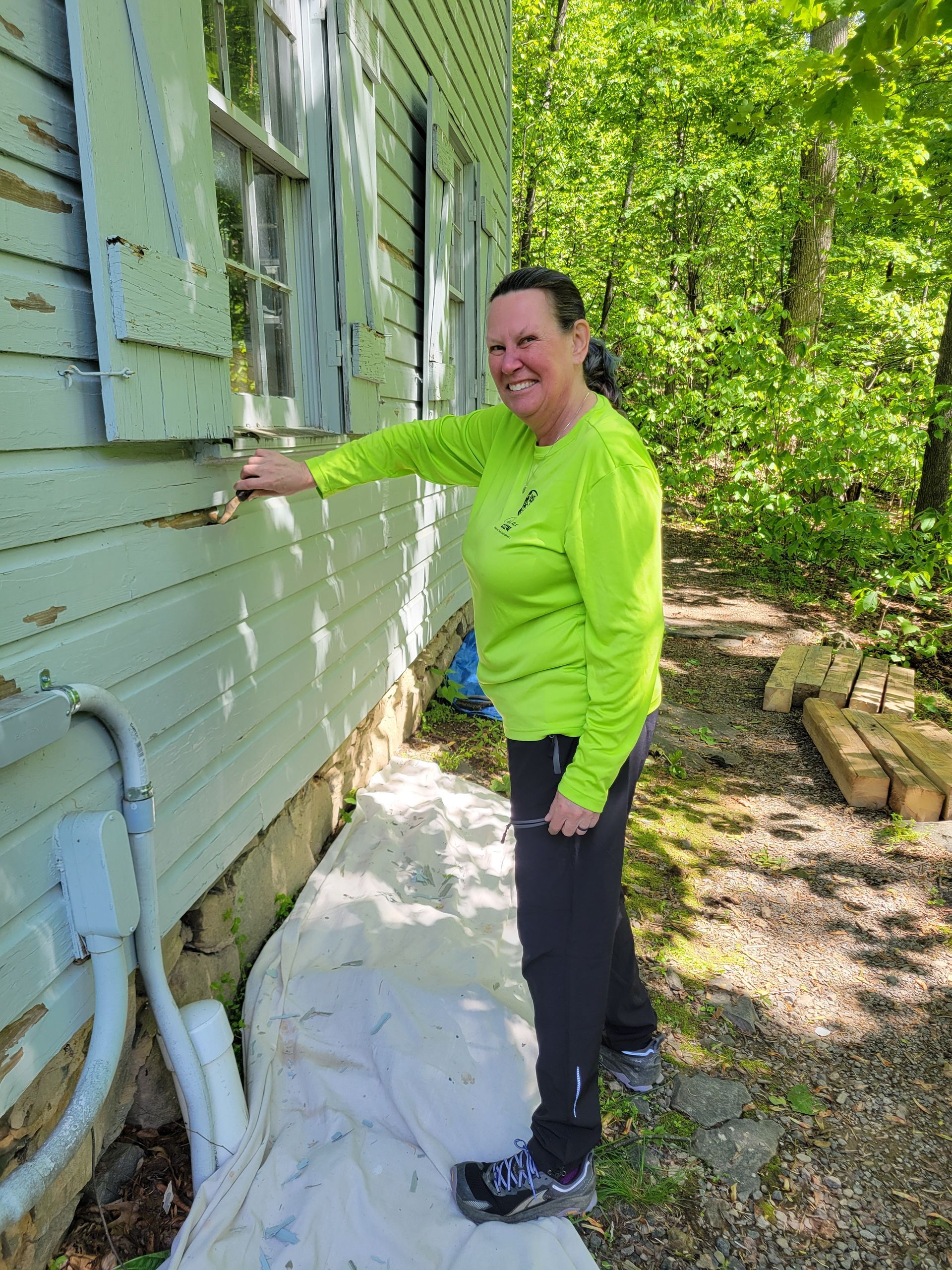 A woman is painting the side of a house.