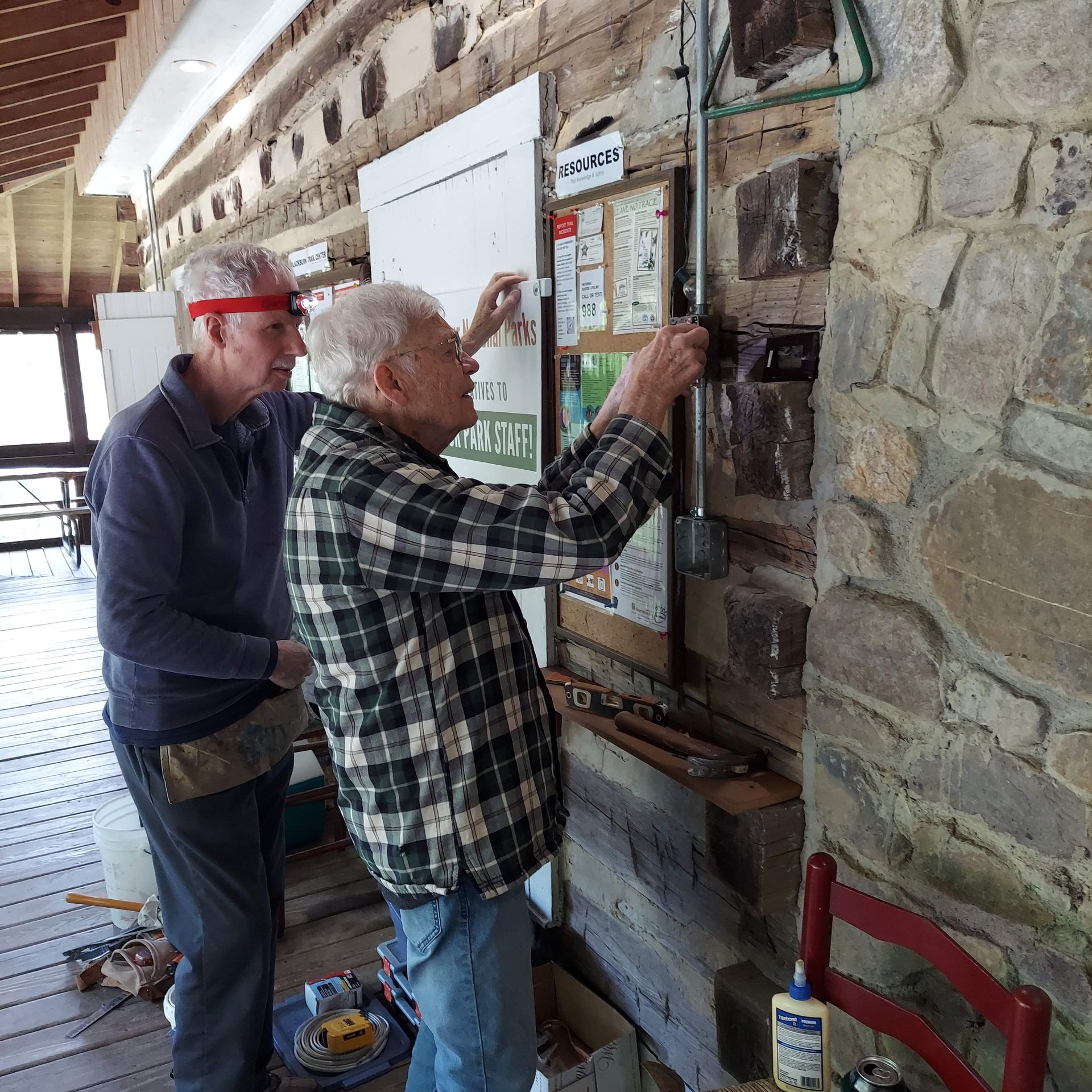 A man in a plaid shirt is working on a wall