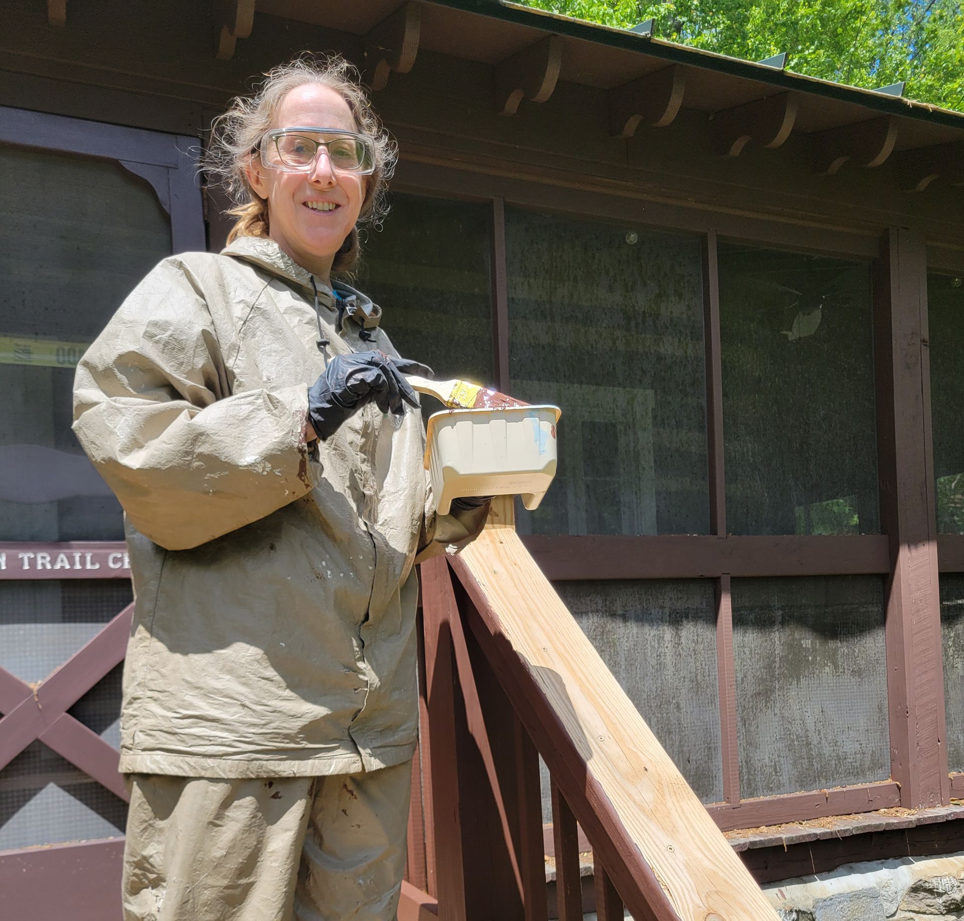 A woman standing on a railing in front of a trail cabin