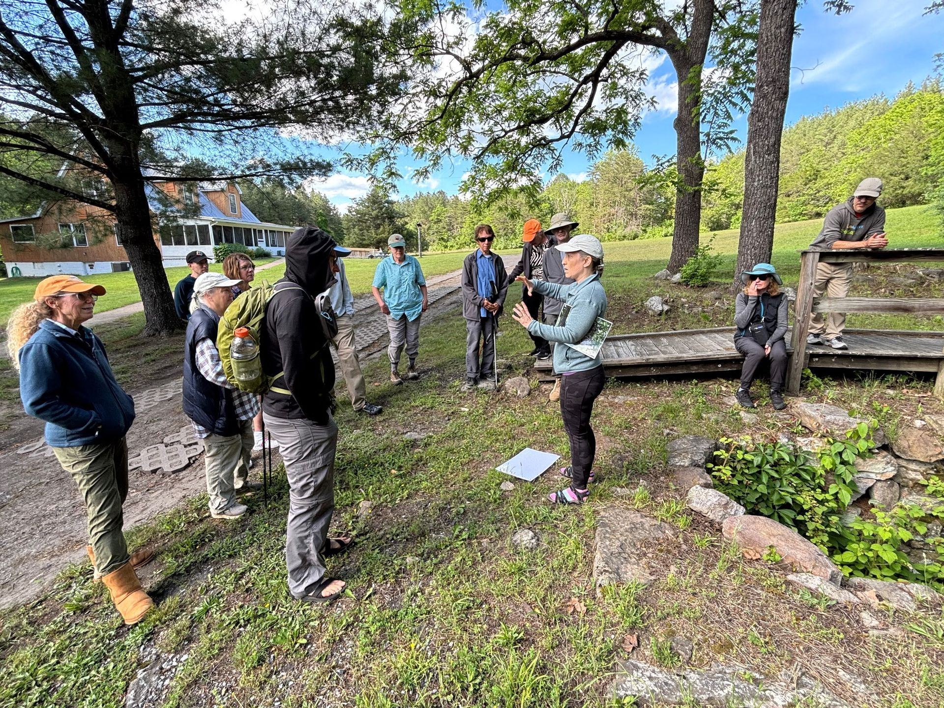 A group of people are standing in a field talking to each other.