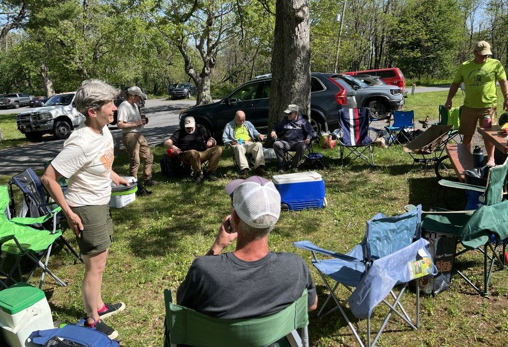 A group of people are sitting in chairs in a park.