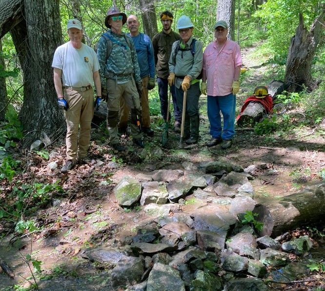 A group of people are standing next to each other in the woods.