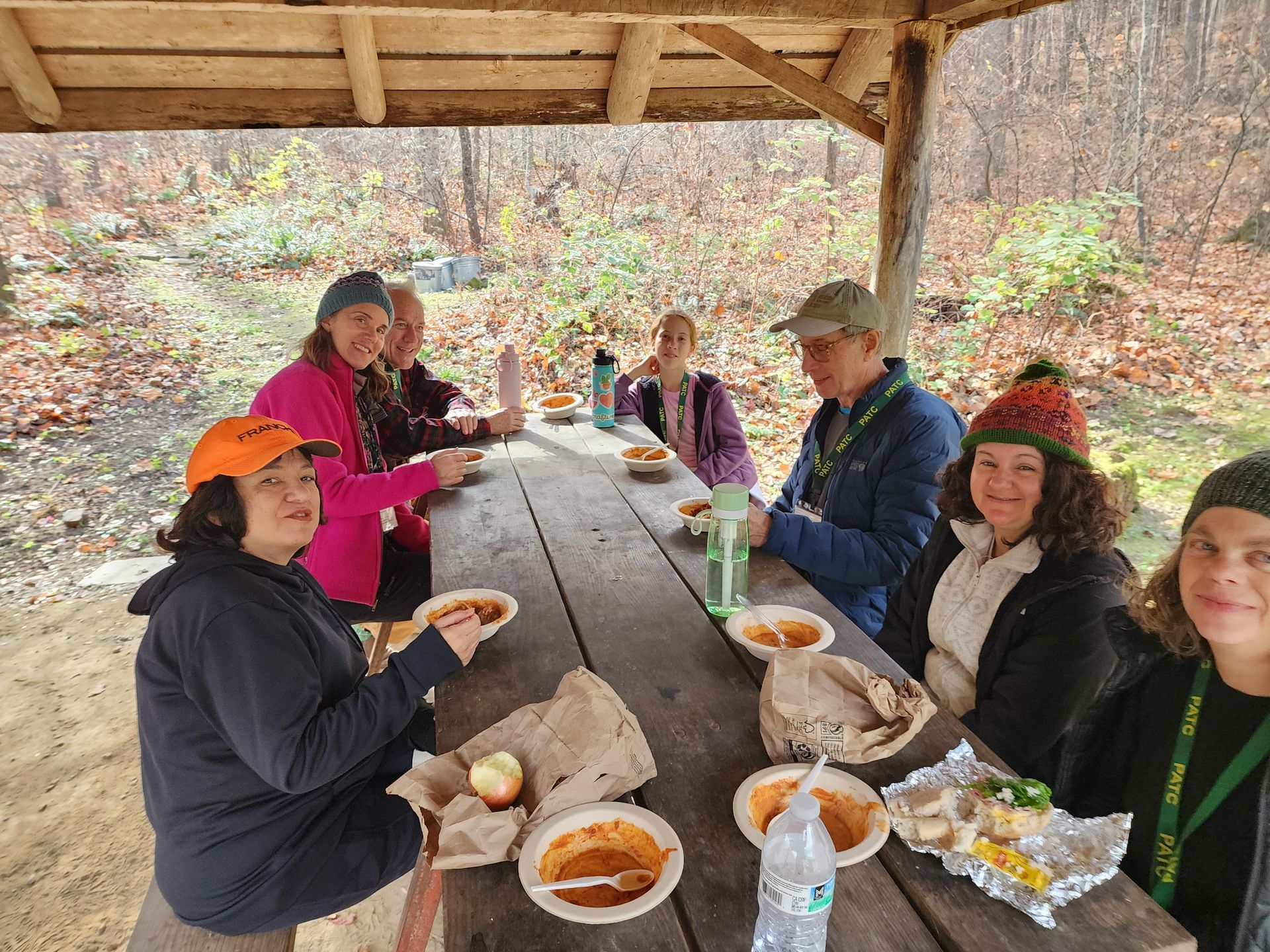 A group of people are sitting at a picnic table eating food.