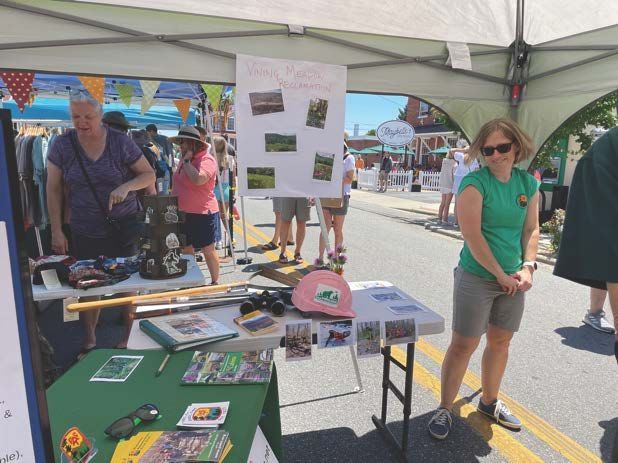 A woman in a green shirt is standing in front of a table