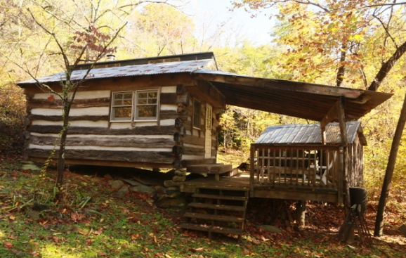 An old log cabin with a porch in the woods
