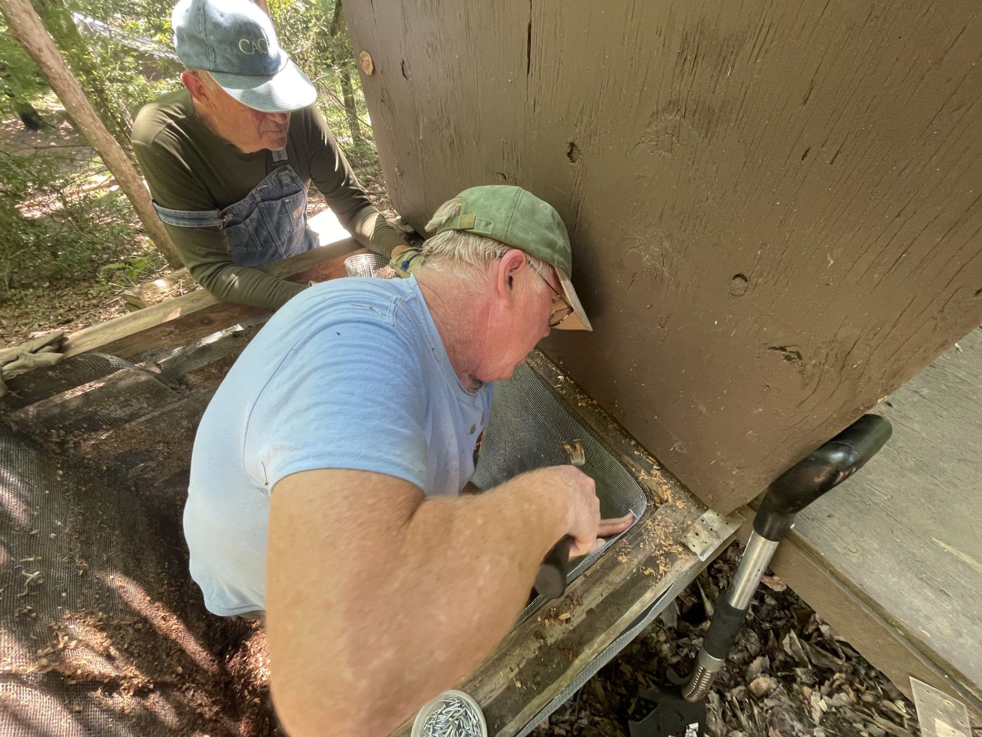 Two men are working on a wooden structure.