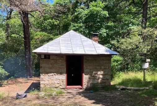 A small stone cabin in the middle of a forest.