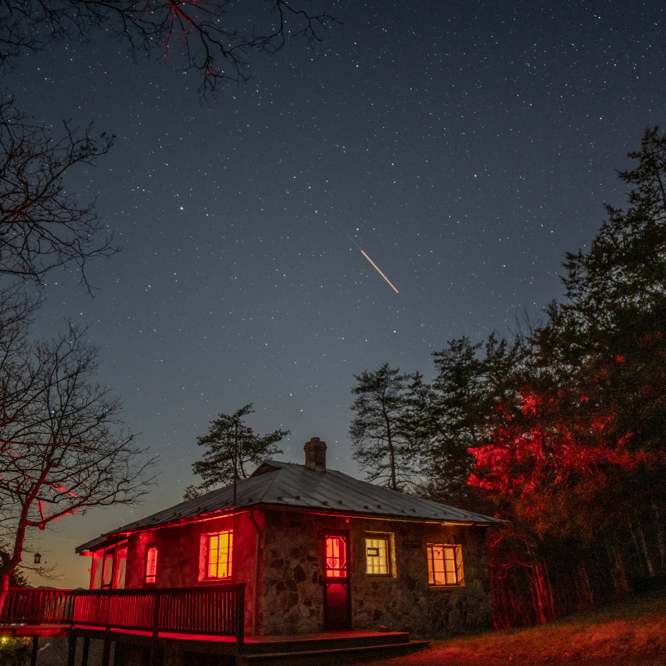 A house is lit up at night with a starry sky in the background.