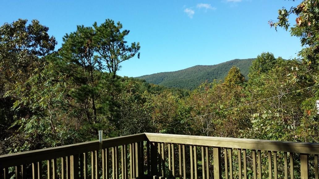 A wooden deck overlooking a forest with mountains in the background