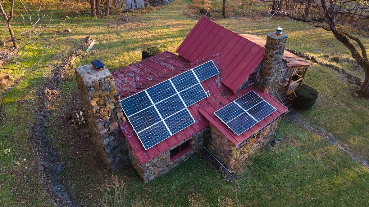 An aerial view of a small house with solar panels on the roof.