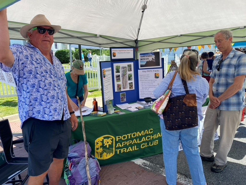 A group of people are standing around a table that says potomac appalachian trail club.