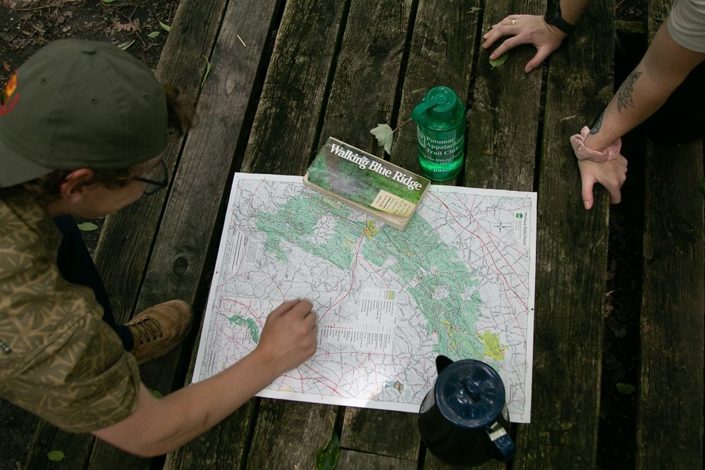 A group of people are sitting at a picnic table looking at a map.