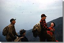 A group of people with backpacks are standing on top of a mountain.