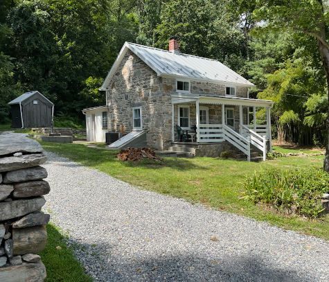 A stone house with a porch and a stone wall