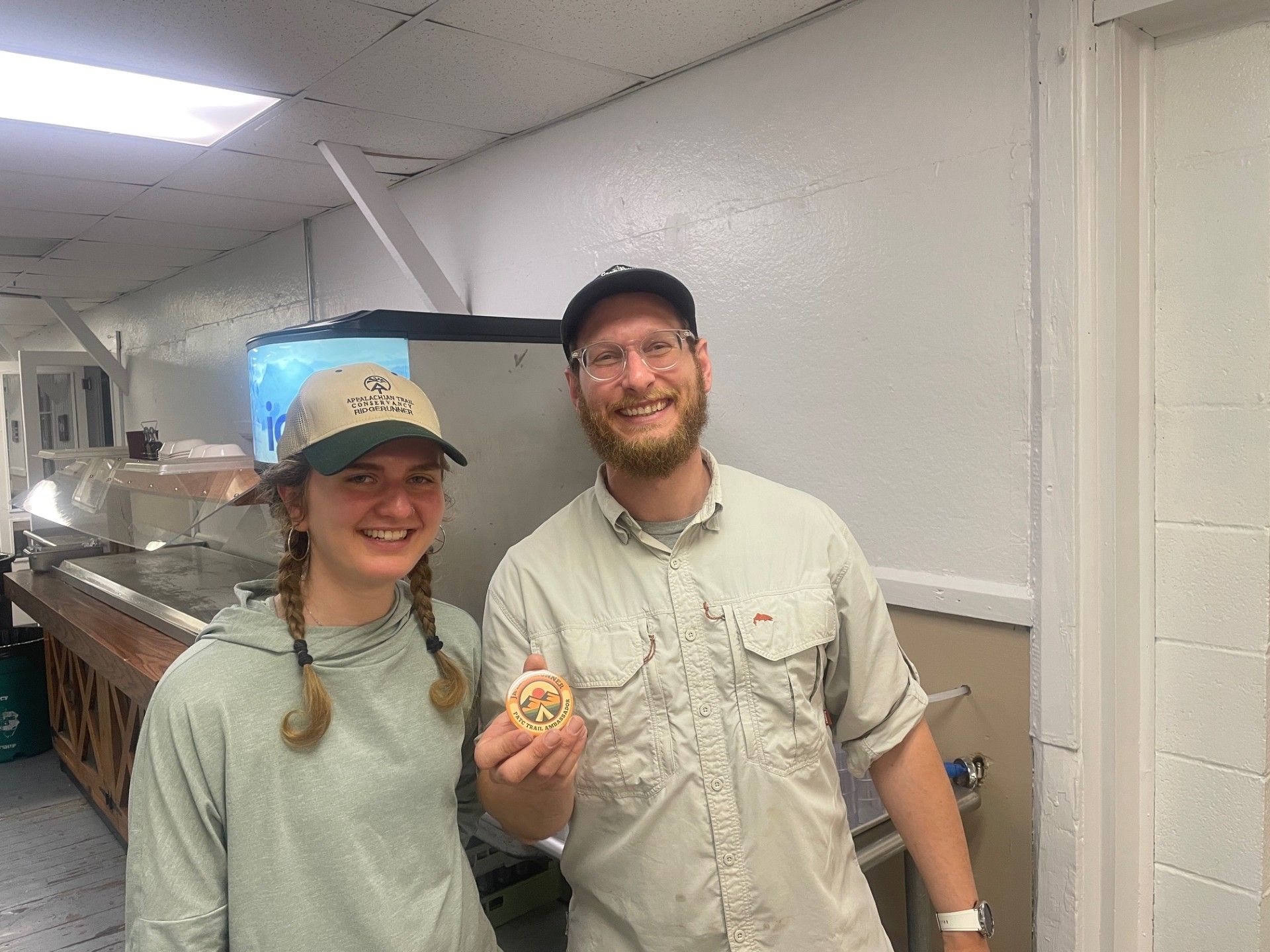 A man and a woman are standing next to each other in a kitchen holding a cookie.