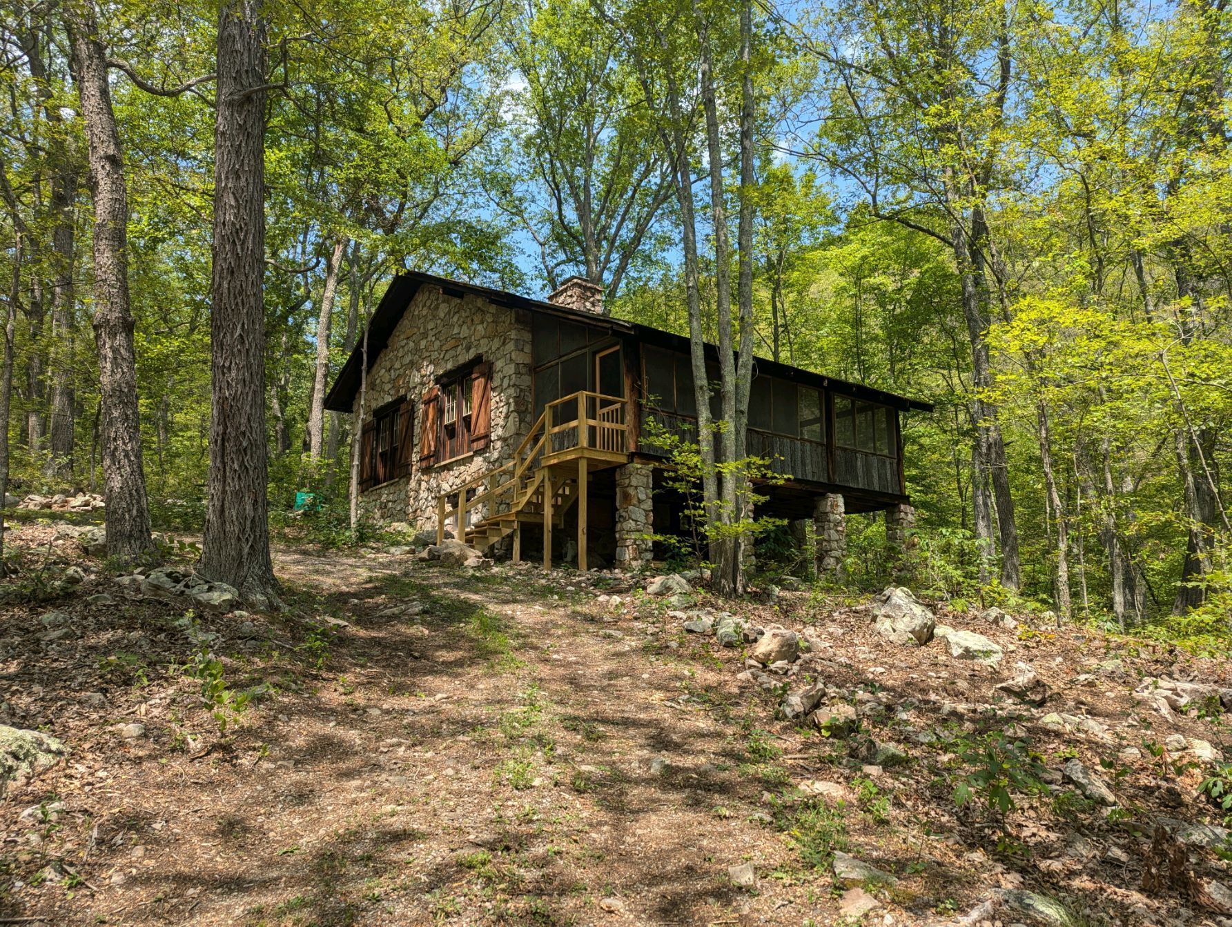 A stone cabin is sitting on top of a hill in the middle of a forest.