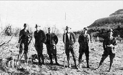 A black and white photo of a group of men standing in a field.