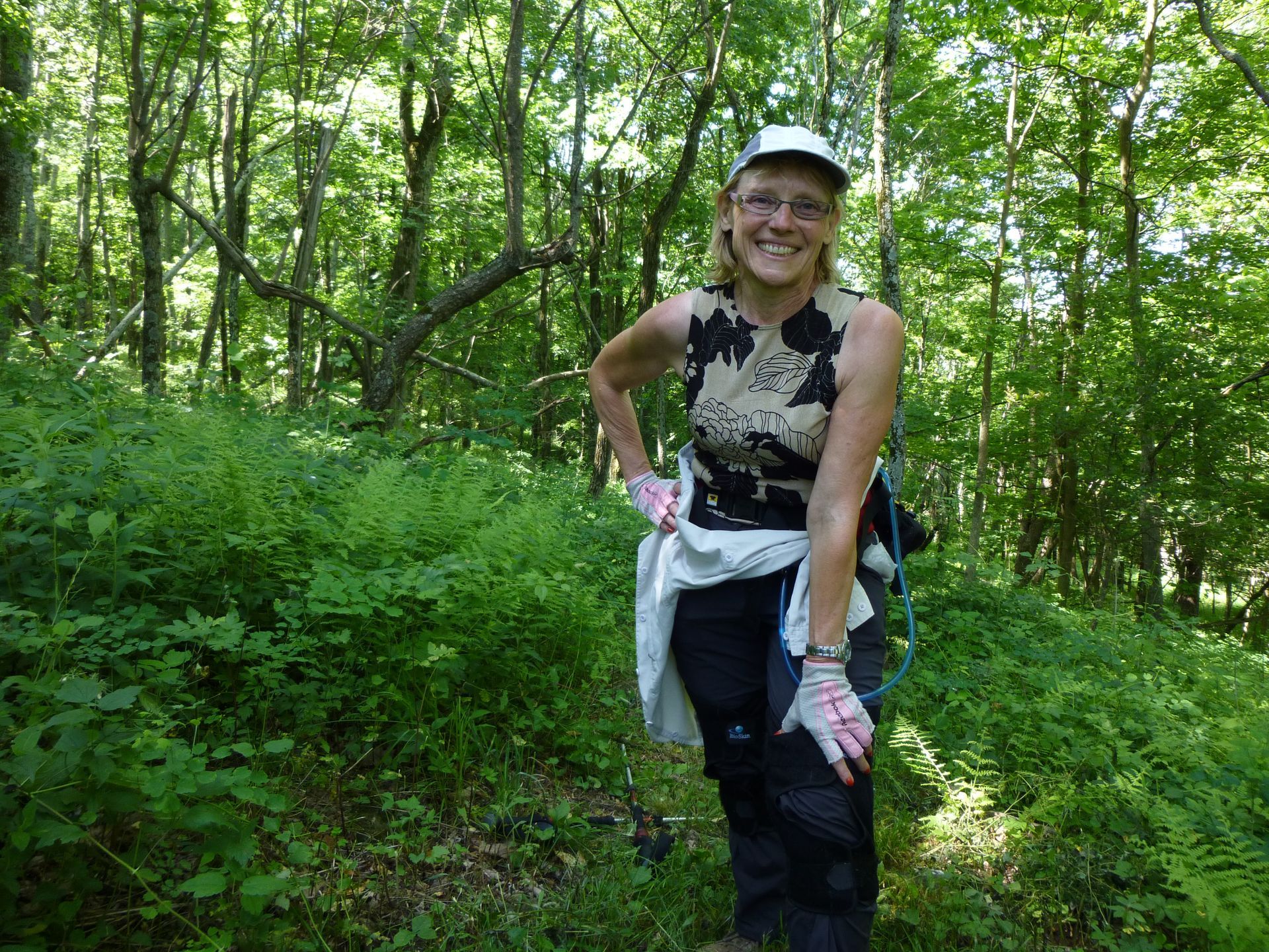 A woman is standing in the middle of a forest with her hands on her hips.