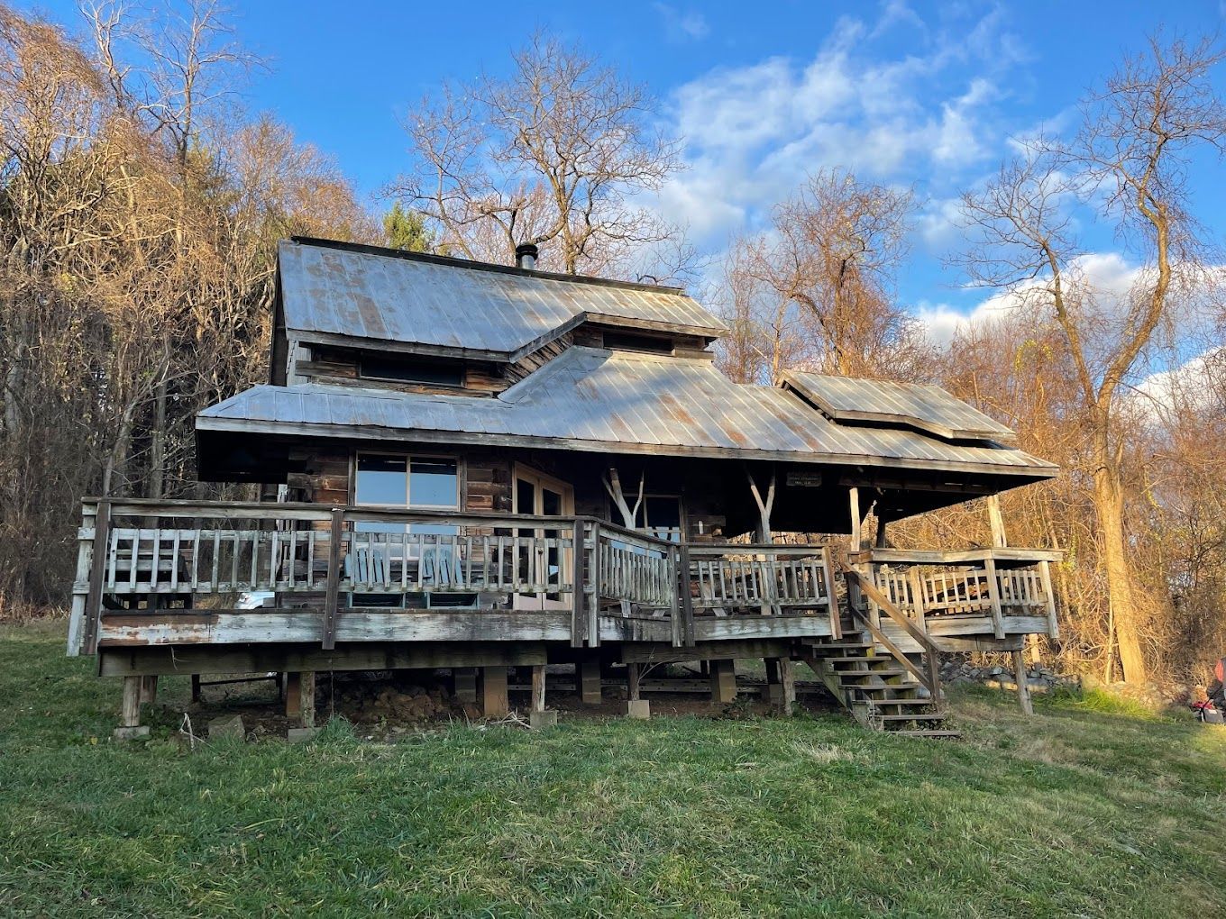A large log cabin with a metal roof is sitting in the middle of a grassy field.