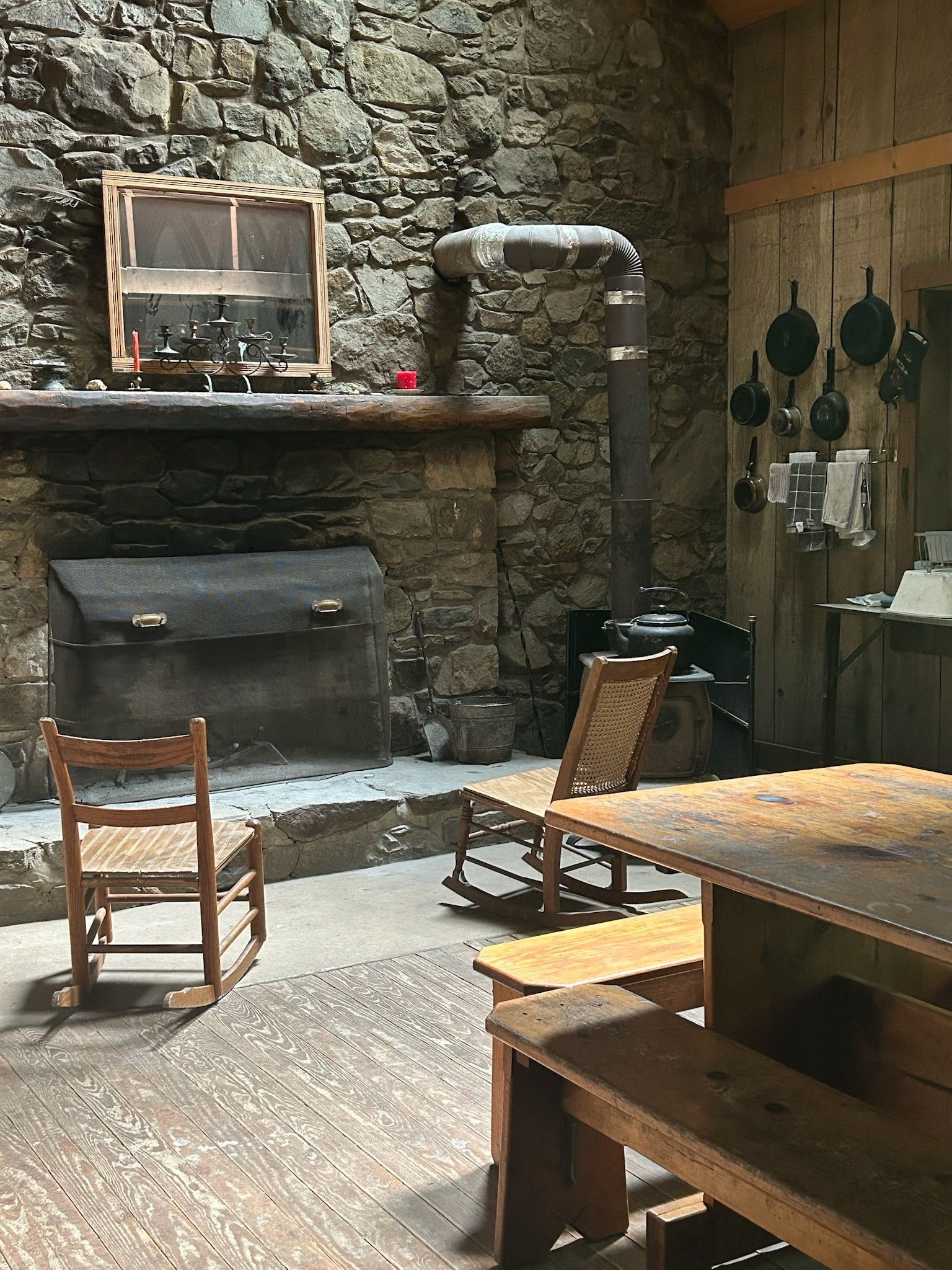 A room with rocking chairs , a table and a fireplace.