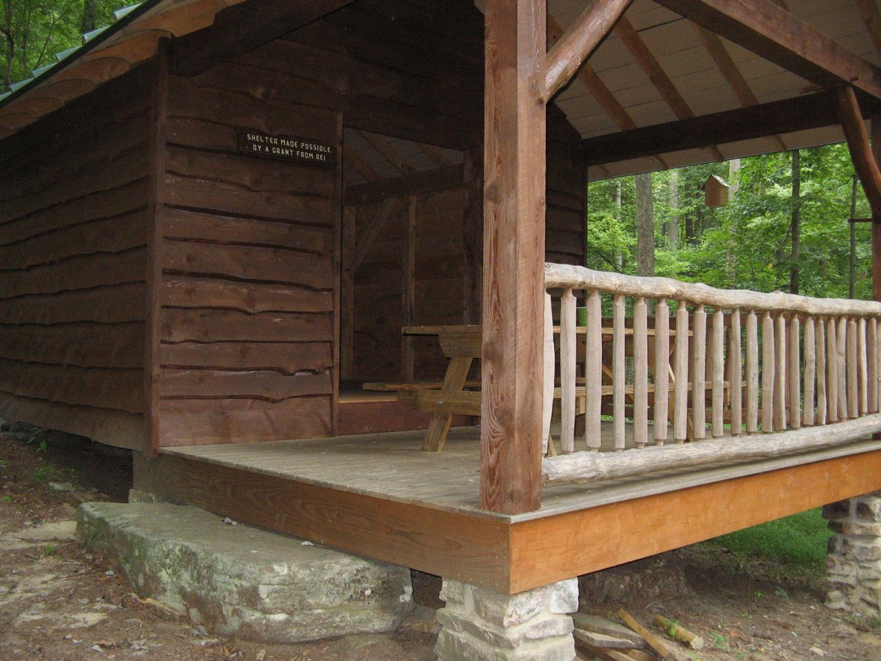 A small wooden cabin with a porch in the woods