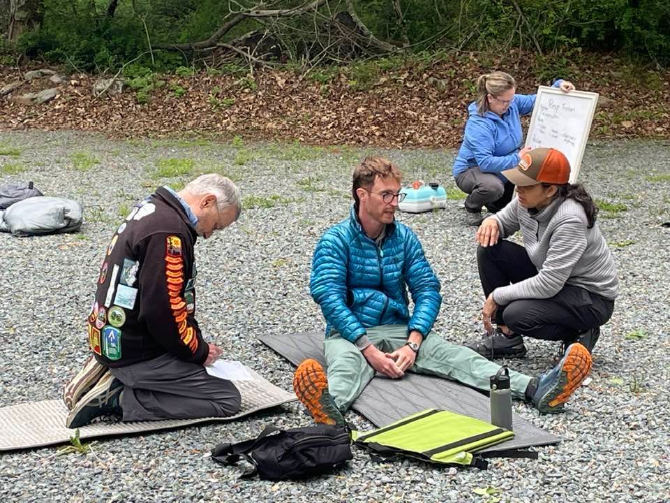 A group of people are sitting on the ground talking to each other.