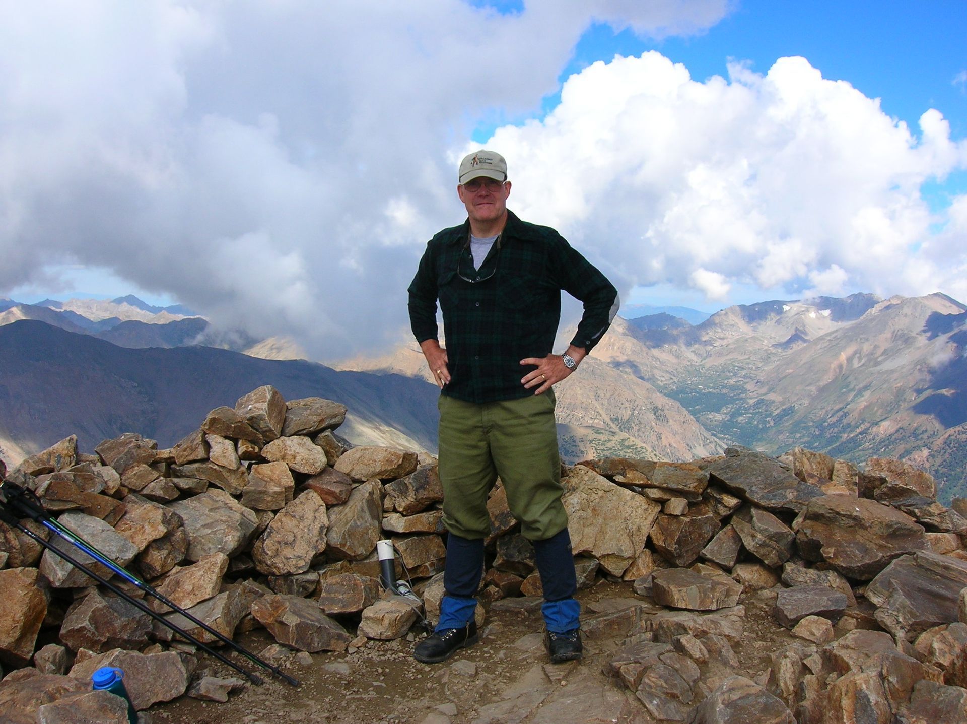 A man standing on top of a rocky hill with mountains in the background