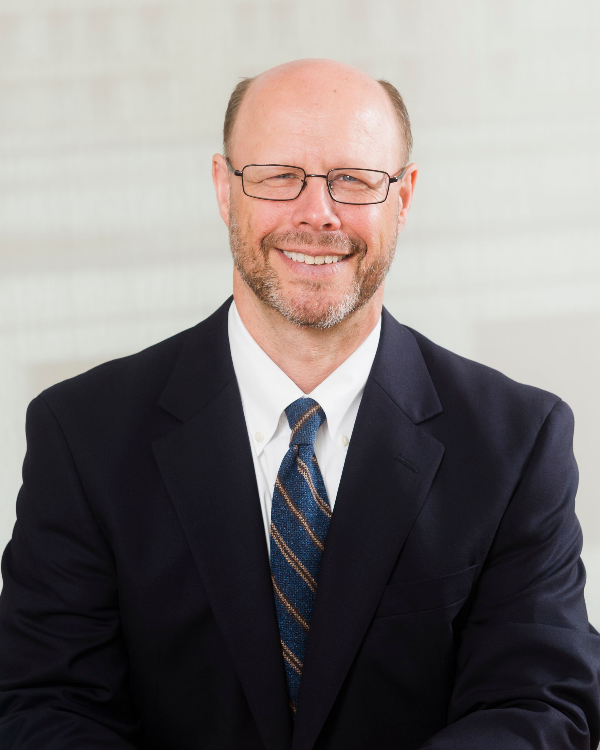 A man in a suit and tie is smiling for the camera