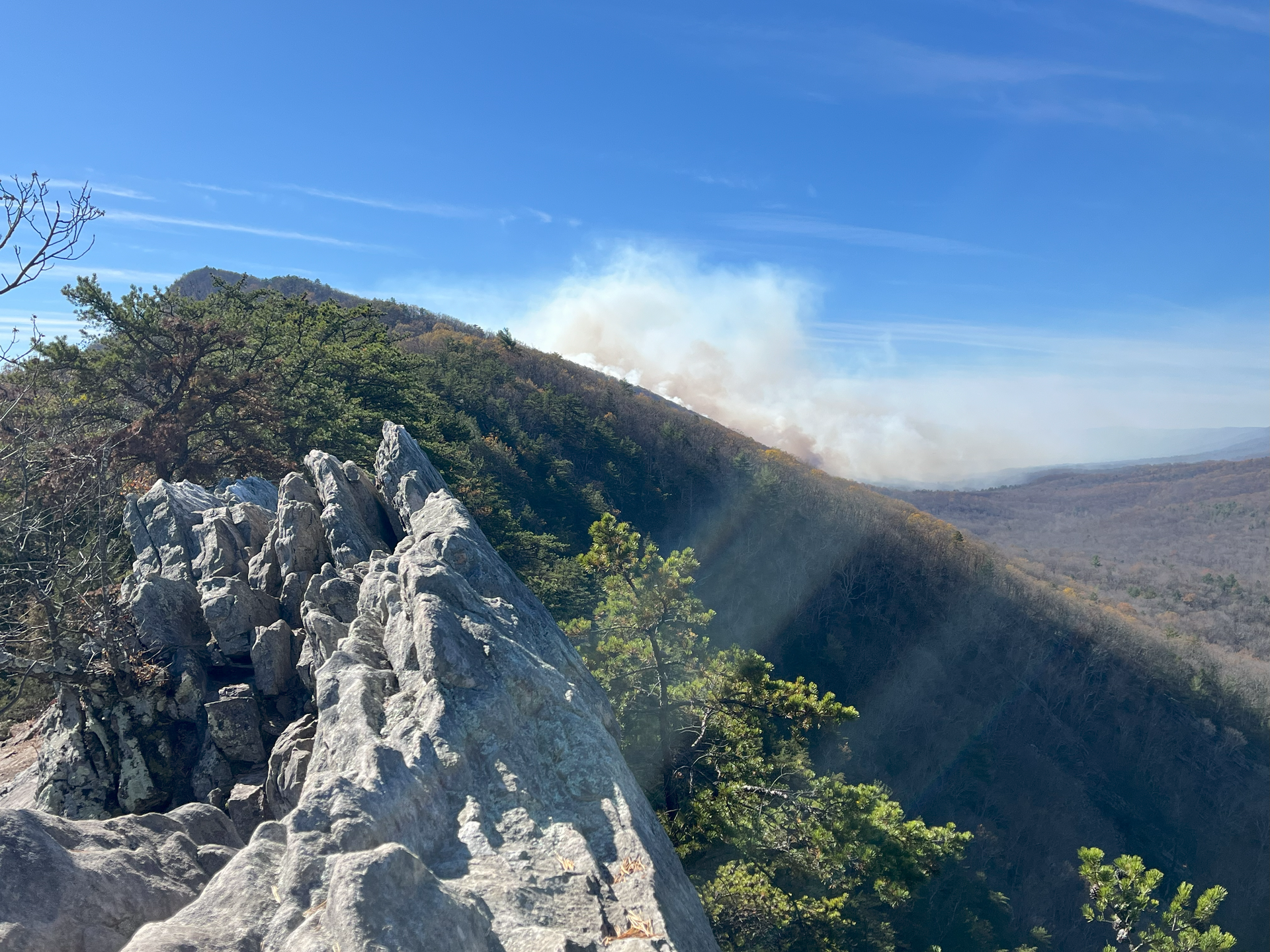 A mountain covered in trees and rocks with smoke coming out of it.