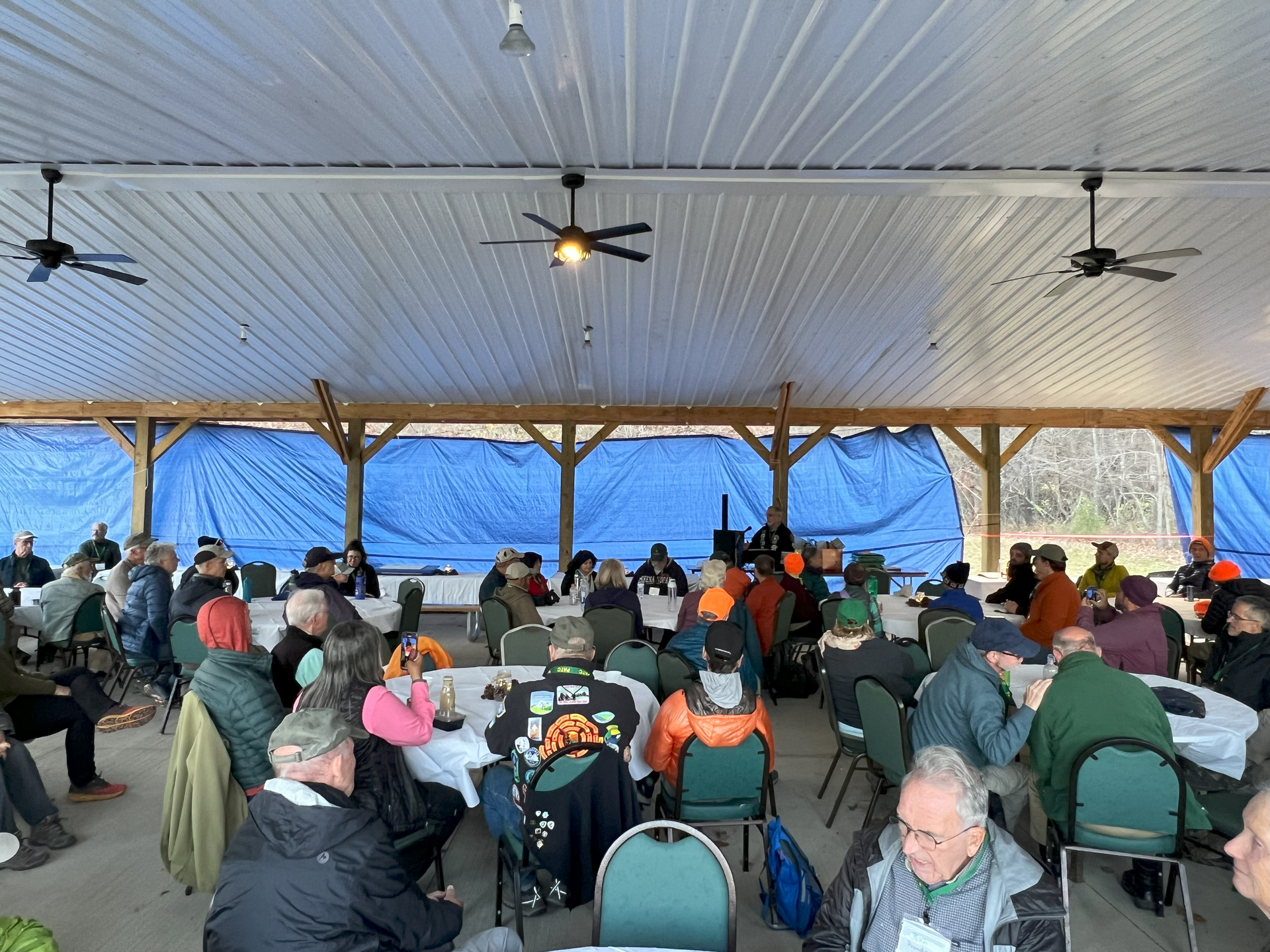 A large group of people are sitting at tables under a tent.