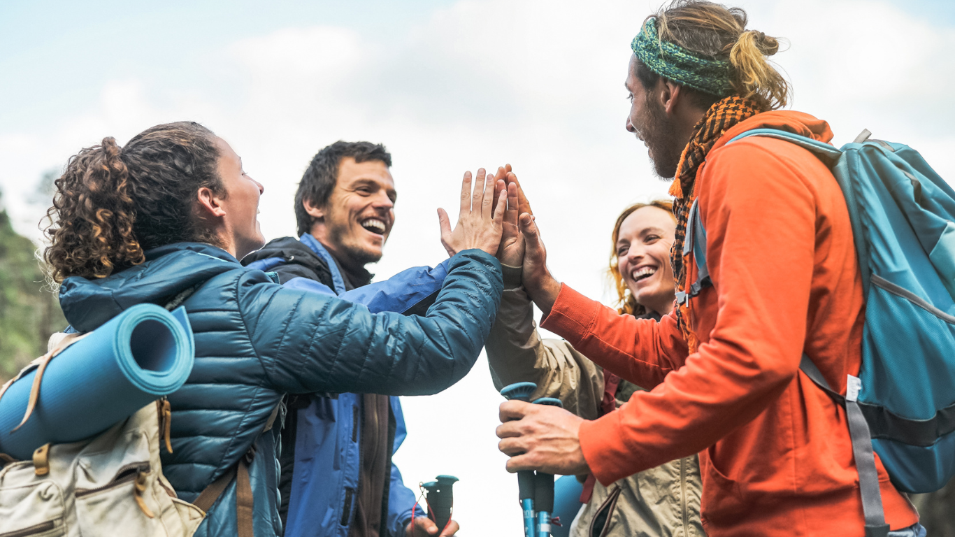 A group of people with backpacks are giving each other a high five.