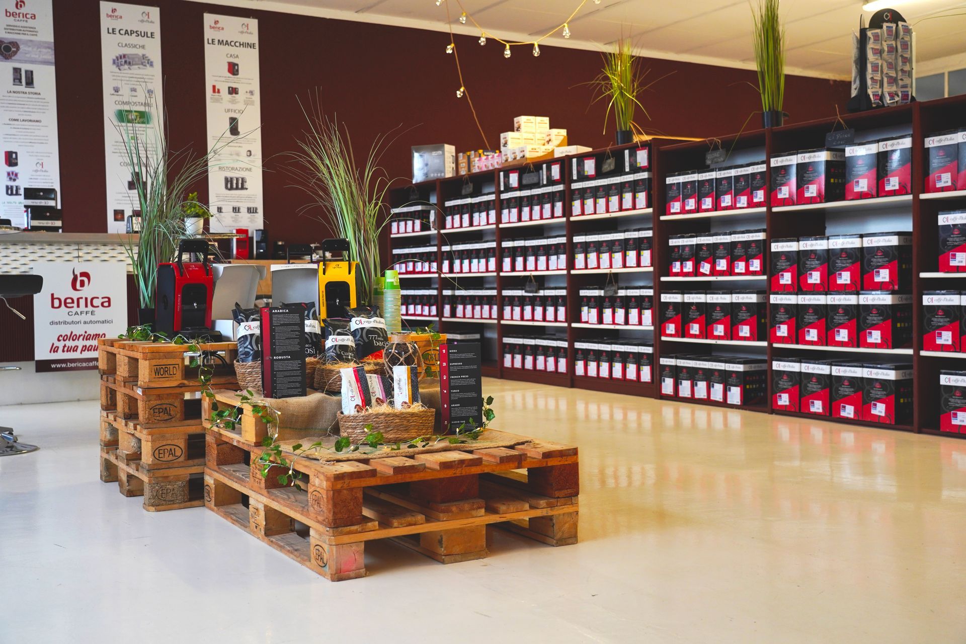 All'interno di un negozio, si trova un espositore per prodotti al coperto, con scaffali impilati di articoli rossi e neri e tavoli in legno realizzati con pallet.