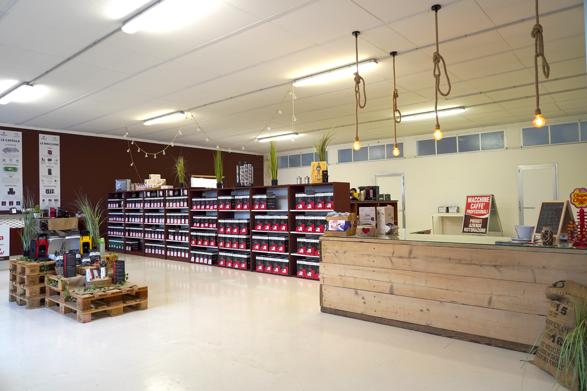 Interno di un supermercato con scaffali pieni di prodotti e un bancone cassa in legno.