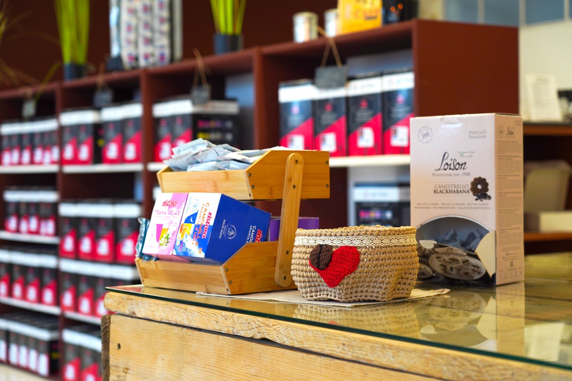 Cesti di vimini e prodotti confezionati sul bancone di una panetteria, con scaffali pieni di barattoli sullo sfondo.