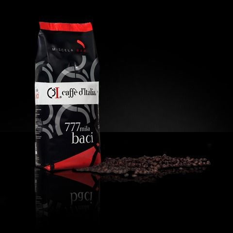 Sacchetto di caffè nero con l'etichetta "Caffè d'Italia 777 mid baci" accanto a chicchi di caffè rovesciati su sfondo nero.
