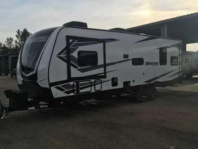 A white and black trailer is parked in a parking lot.