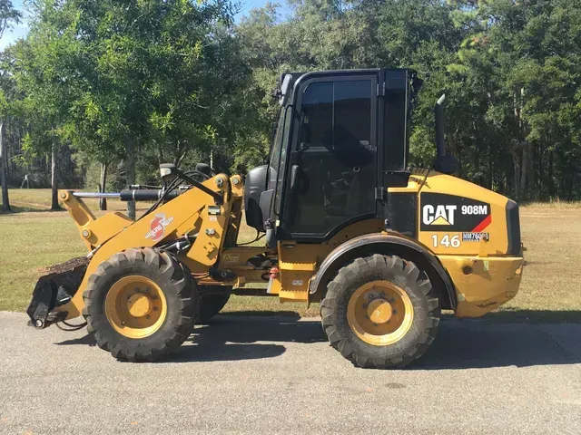 A yellow and black cat wheel loader is parked on the side of the road.