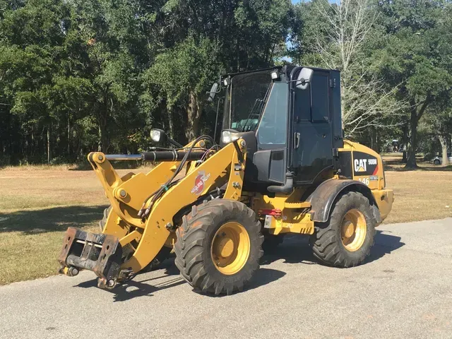 A yellow cat wheel loader is parked on the side of the road.