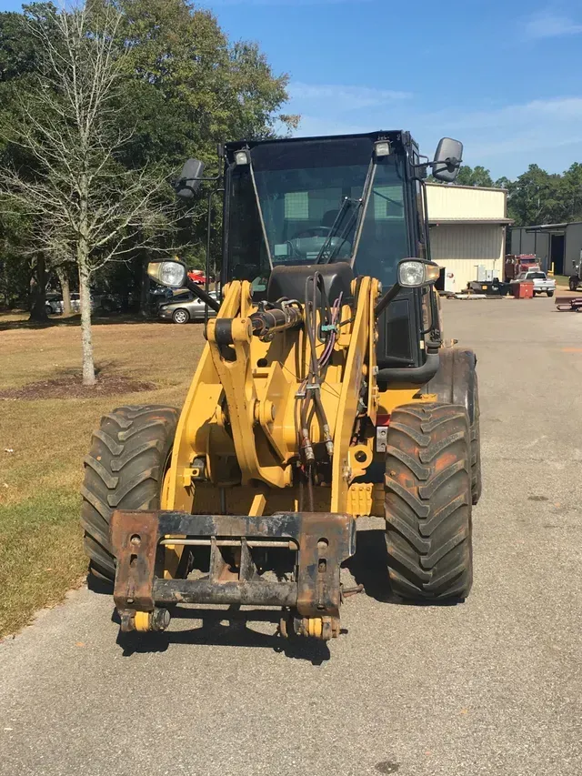A yellow tractor is parked on the side of the road
