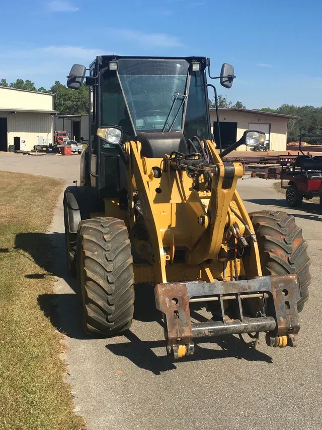 A yellow tractor is parked on the side of the road.